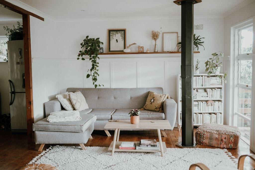 kis nappali világos színű kanapéval és könyvespolccal